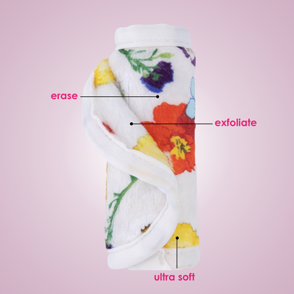 Rolled up Mini Wildflowers MakeUp Eraser with both sides exposed. The short fiber side is labeled as erase, and the long fiber side is labeled as exfoliate.